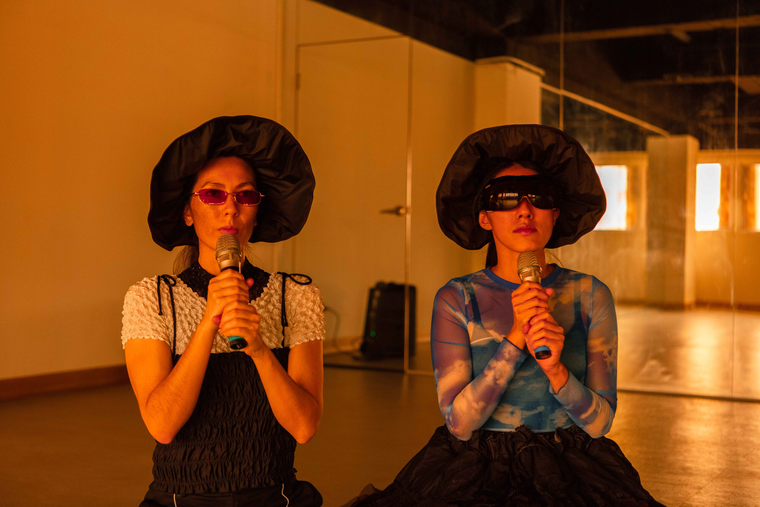 two women in black hat and sunglasses, as well as holding microphones.