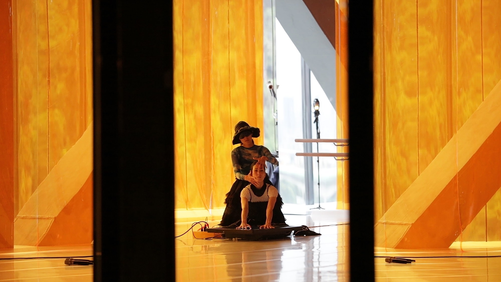 This image is of two women sitting on the floor, in a room with orange filters.